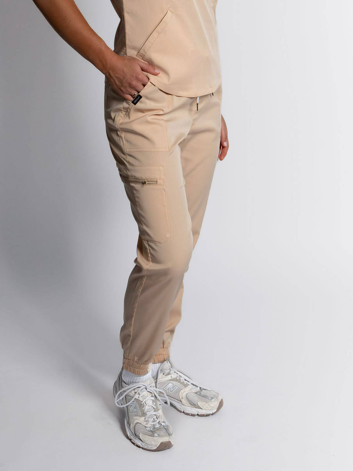 Nurse wearing cream beige slim jogger scrub pants with white background